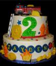 Firefighter themed 2nd Birthday cake,   White Buttercream iced,  2 tiers adorned with fondant stars and hose, Chocolate badge, ladder,fire hydrant, and flames. (Serves 28-55 party slices)